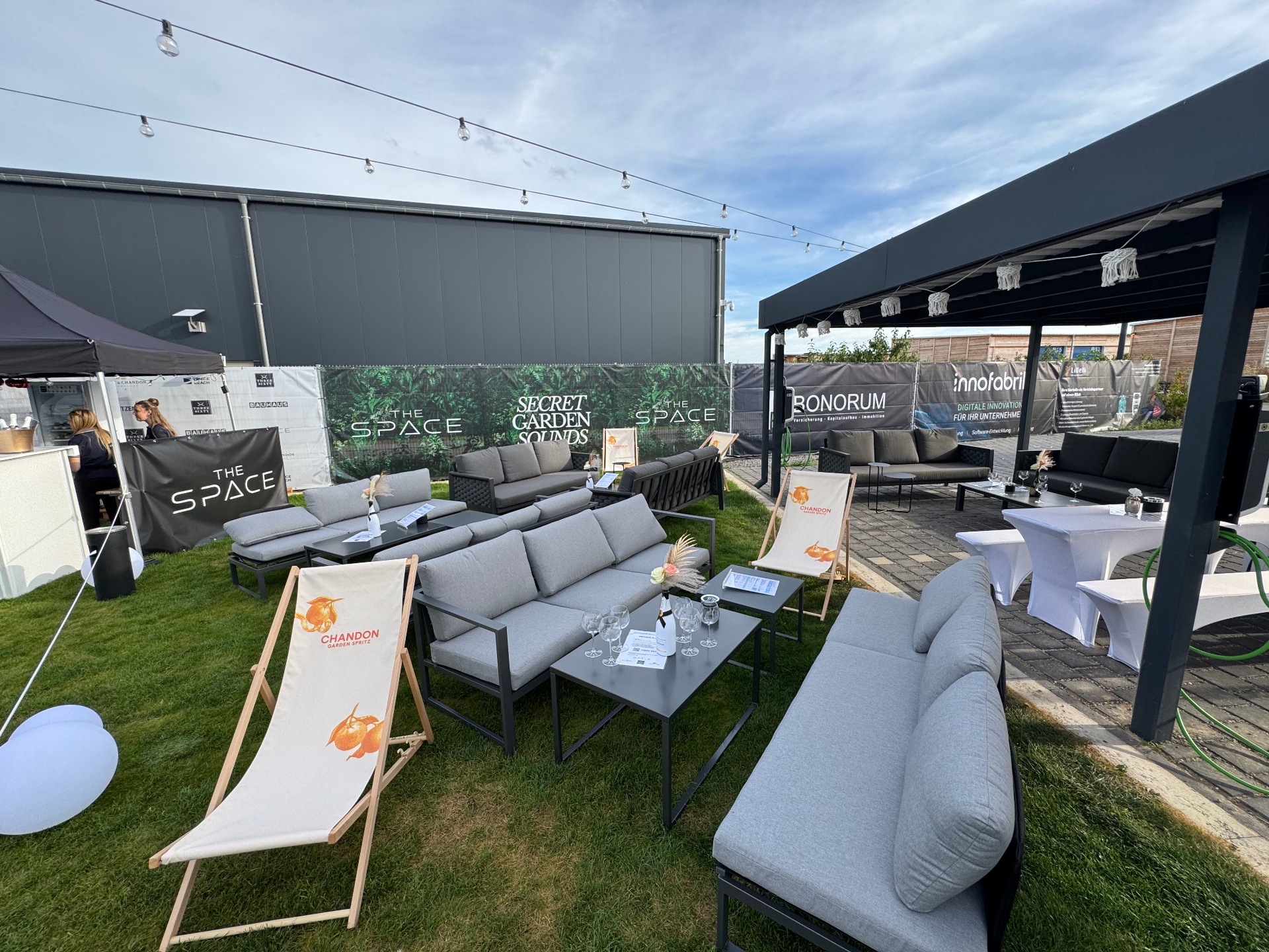 Lounge-Setup von THE SPACE mit Sofas, Liegestühlen und Bar im Freien